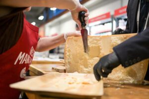 Person cutting cheese at show